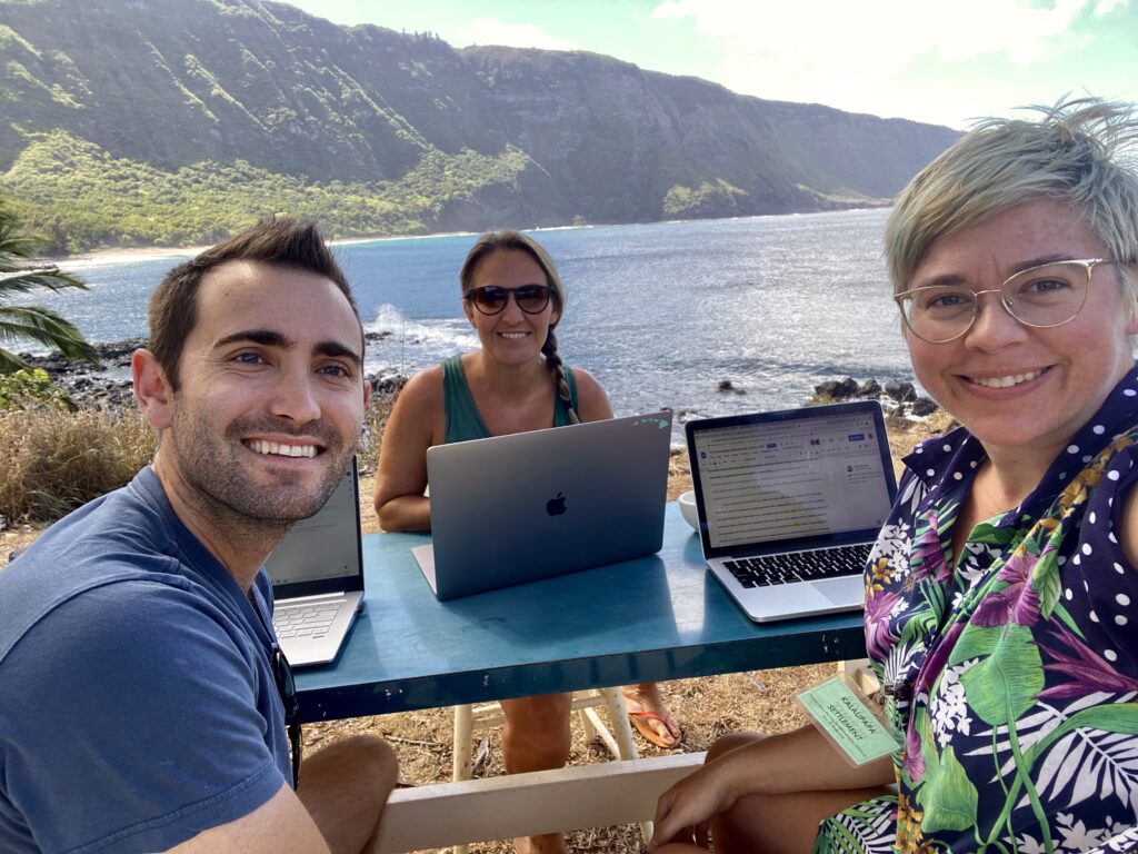 Robin Tinghitella, center, and her fellow researchers pose for a photo while working at a table in Hawaii.